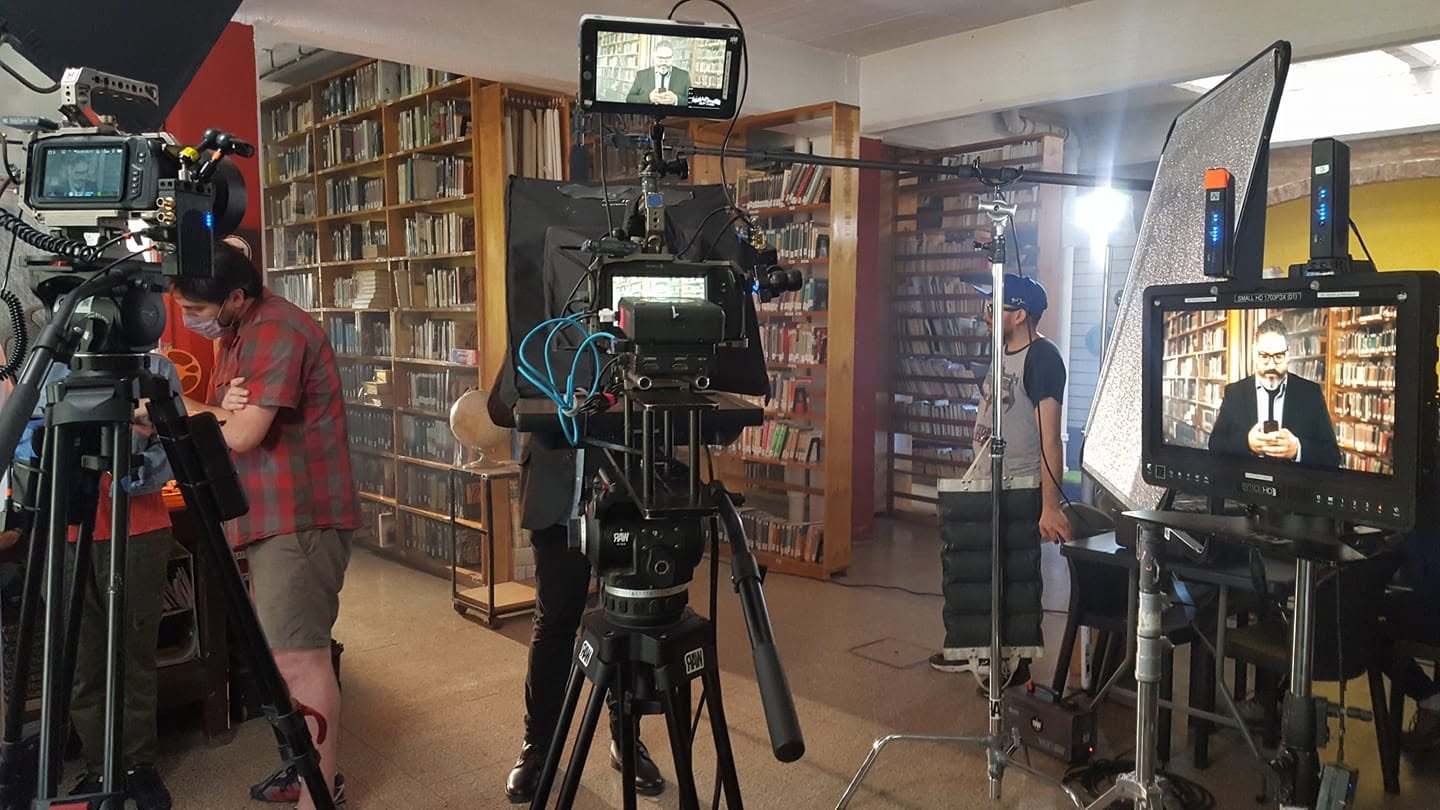 Cámara de cine, iluminación y equipo técnico trabajando durante una producción audiovisual en locación.