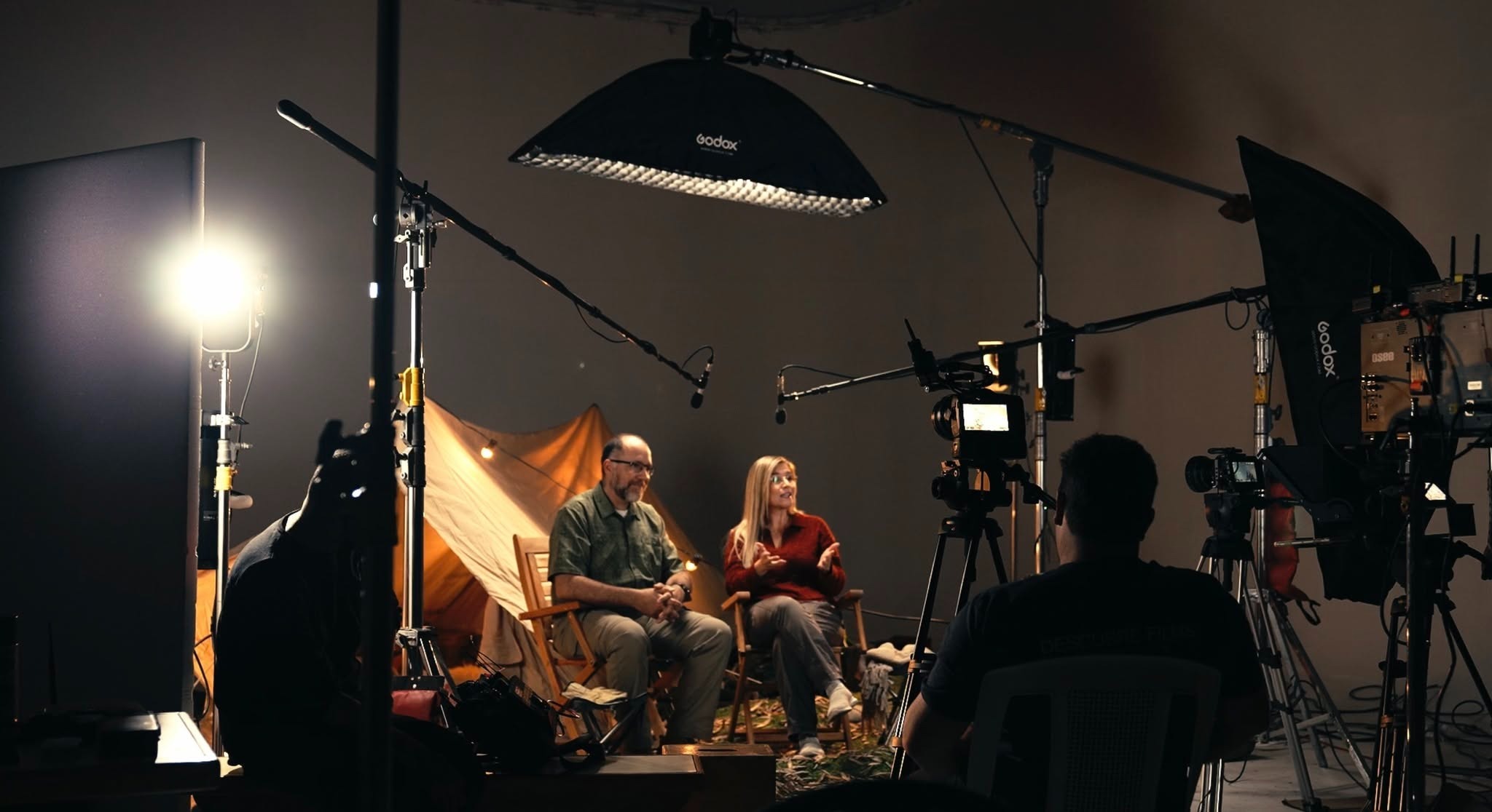 Pareja preparada para una escena mientras el equipo organiza la iluminación alrededor del set.