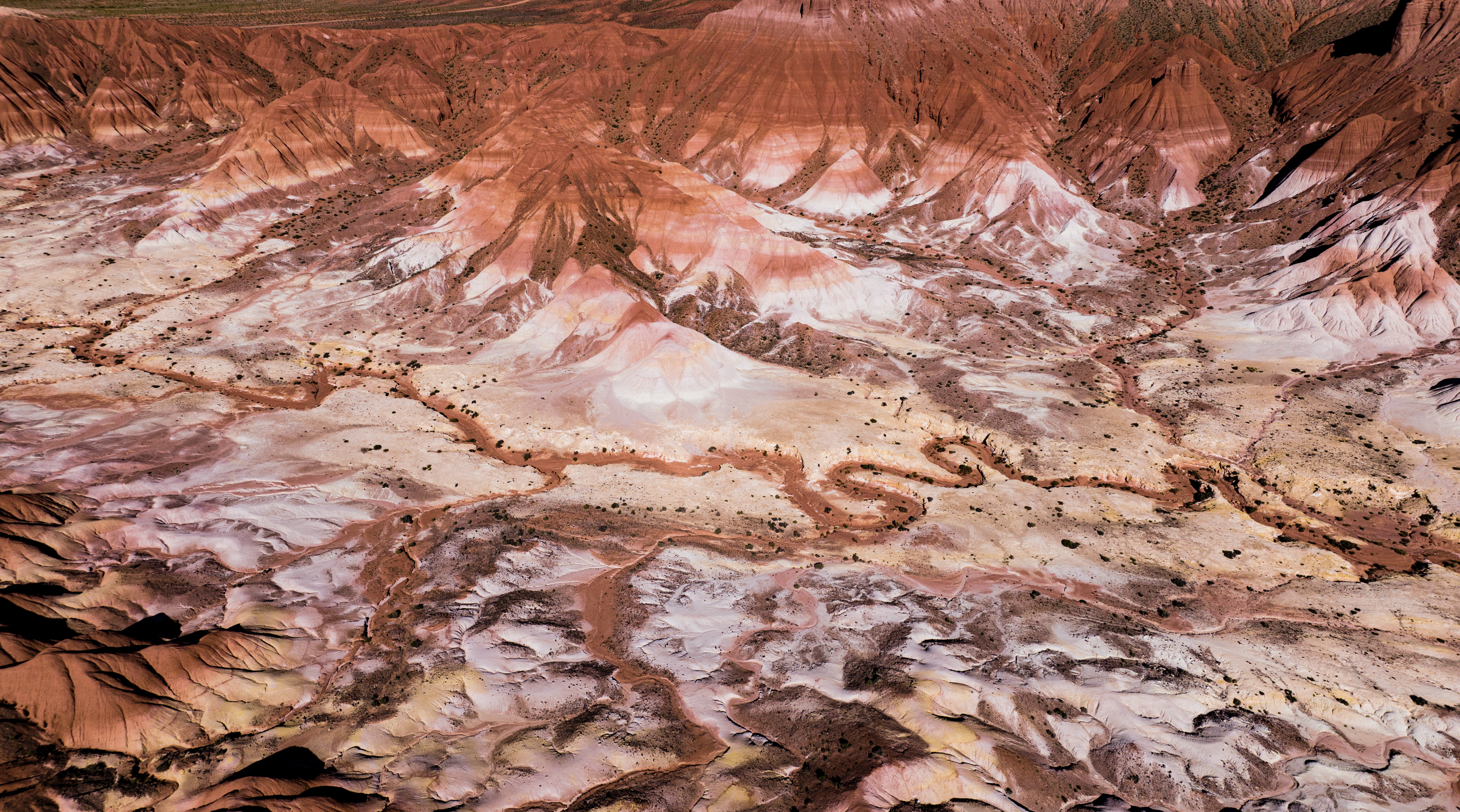 Vista aérea de formaciones rocosas de colores rojizos y rosados en un paisaje árido.