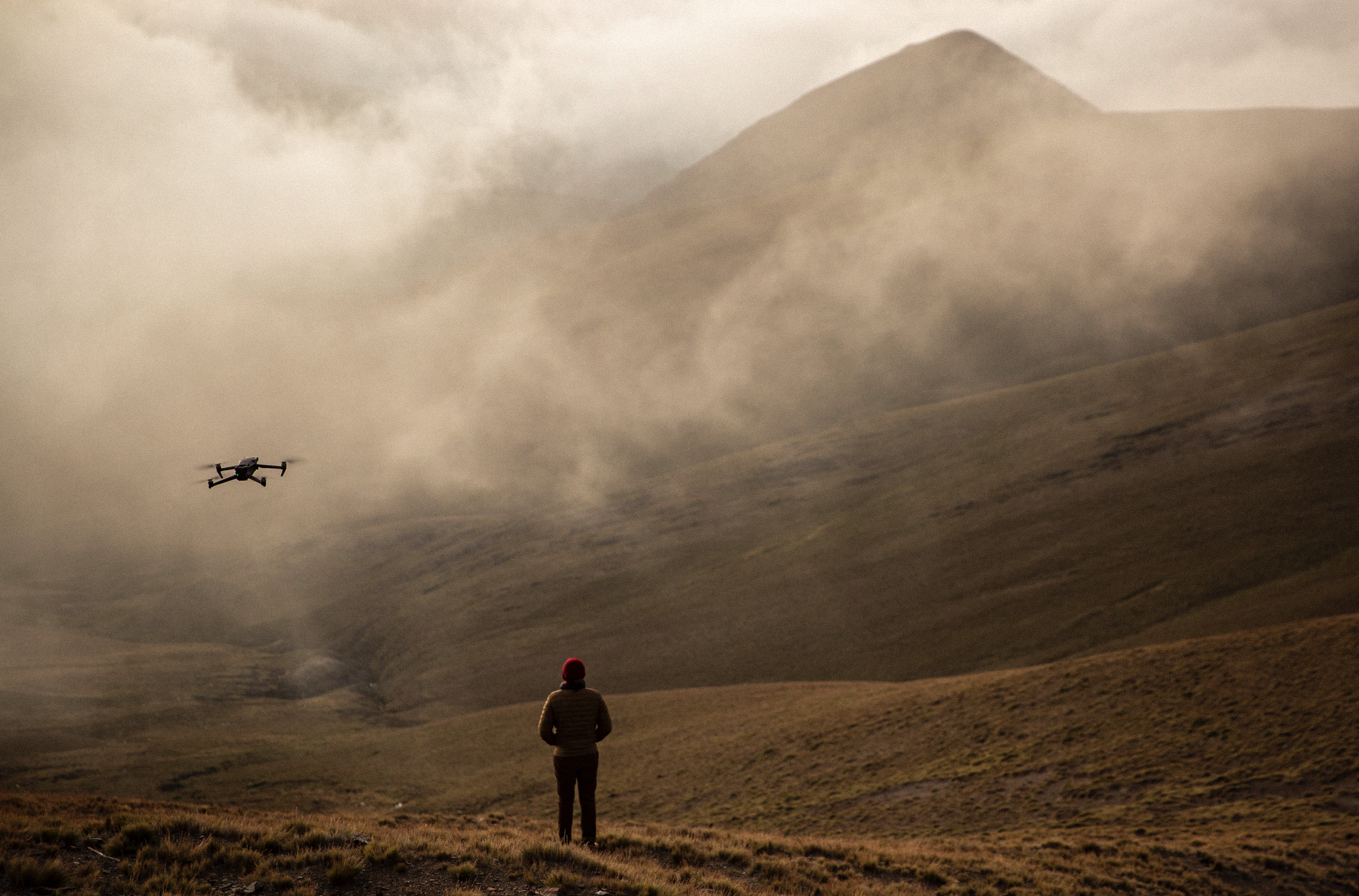 Dron volando frente a una montaña cubierta parcialmente por niebla en un paisaje de Jujuy, Argentina.