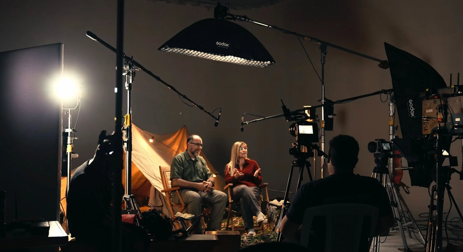 Pareja preparada para una escena mientras el equipo organiza la iluminación alrededor del set.