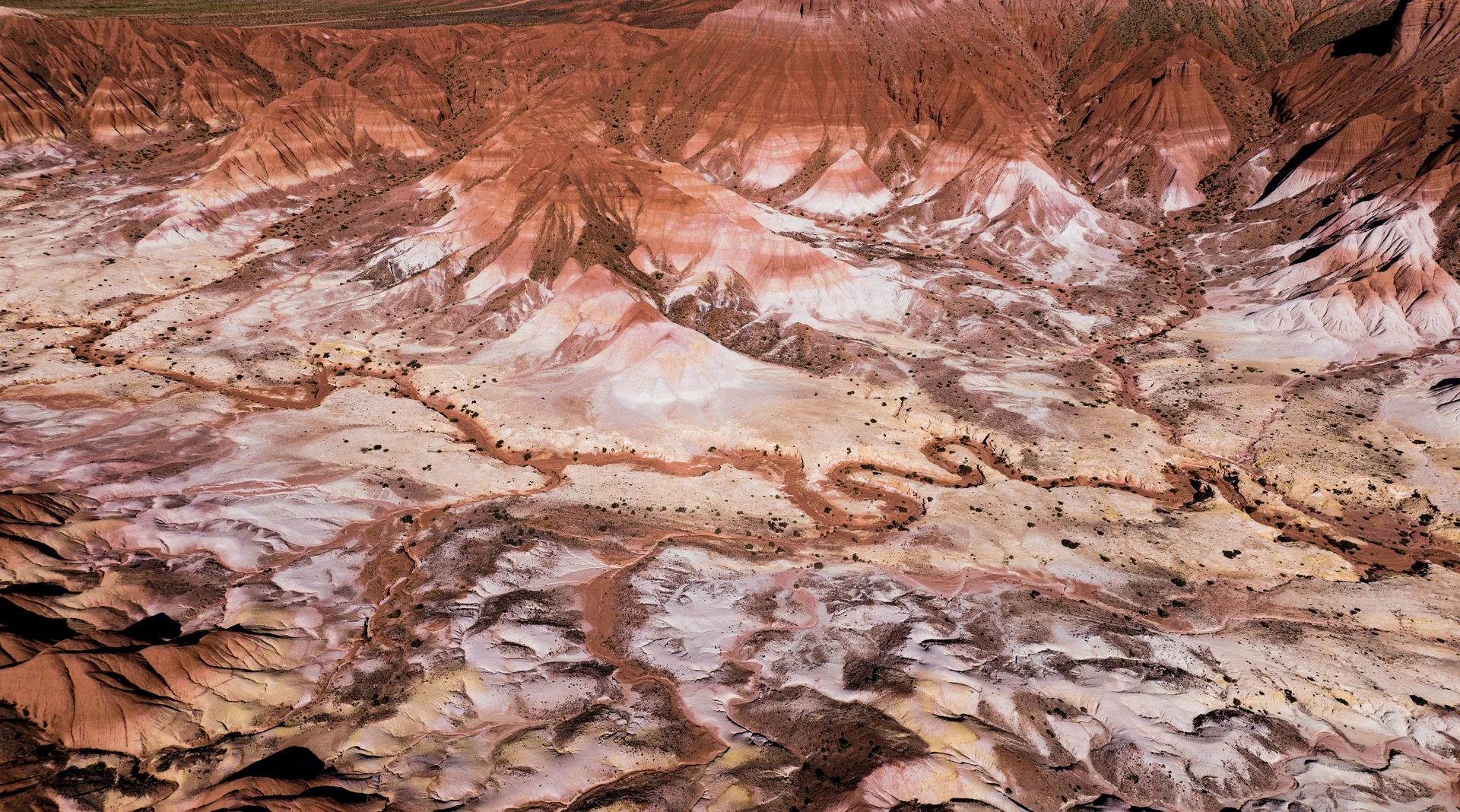 Vista aérea de formaciones rocosas de colores rojizos y rosados en un paisaje árido.