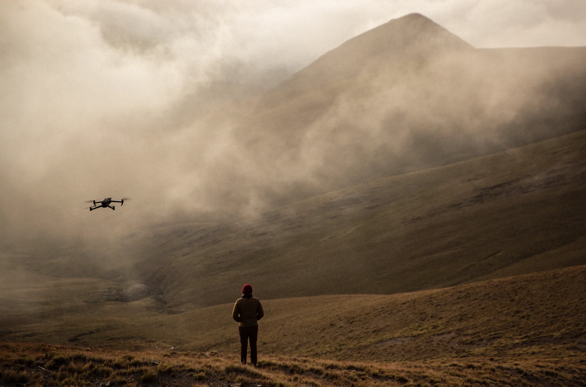 Dron volando frente a una montaña cubierta parcialmente por niebla en un paisaje de Jujuy, Argentina.