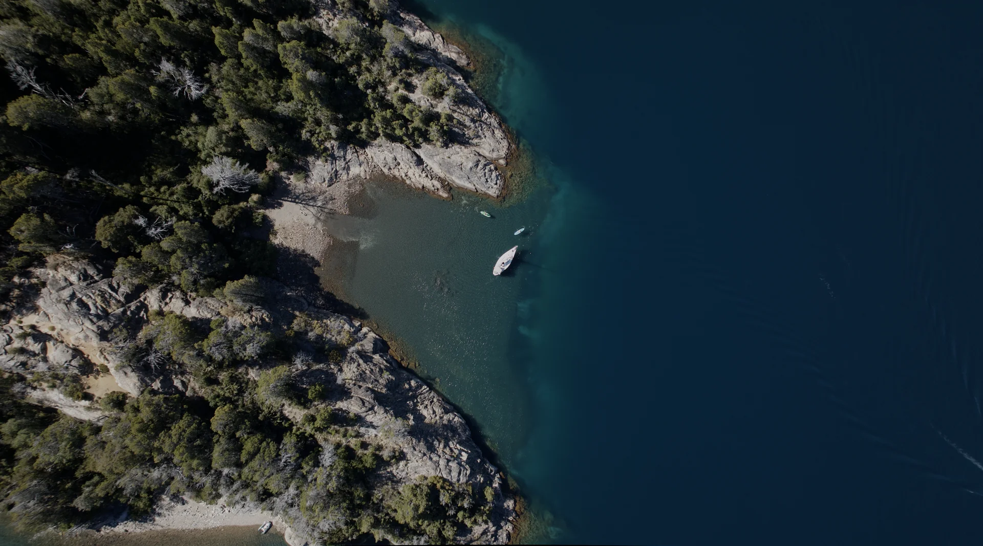 Vista aérea de una costa rocosa con una embarcación navegando junto a aguas profundas.